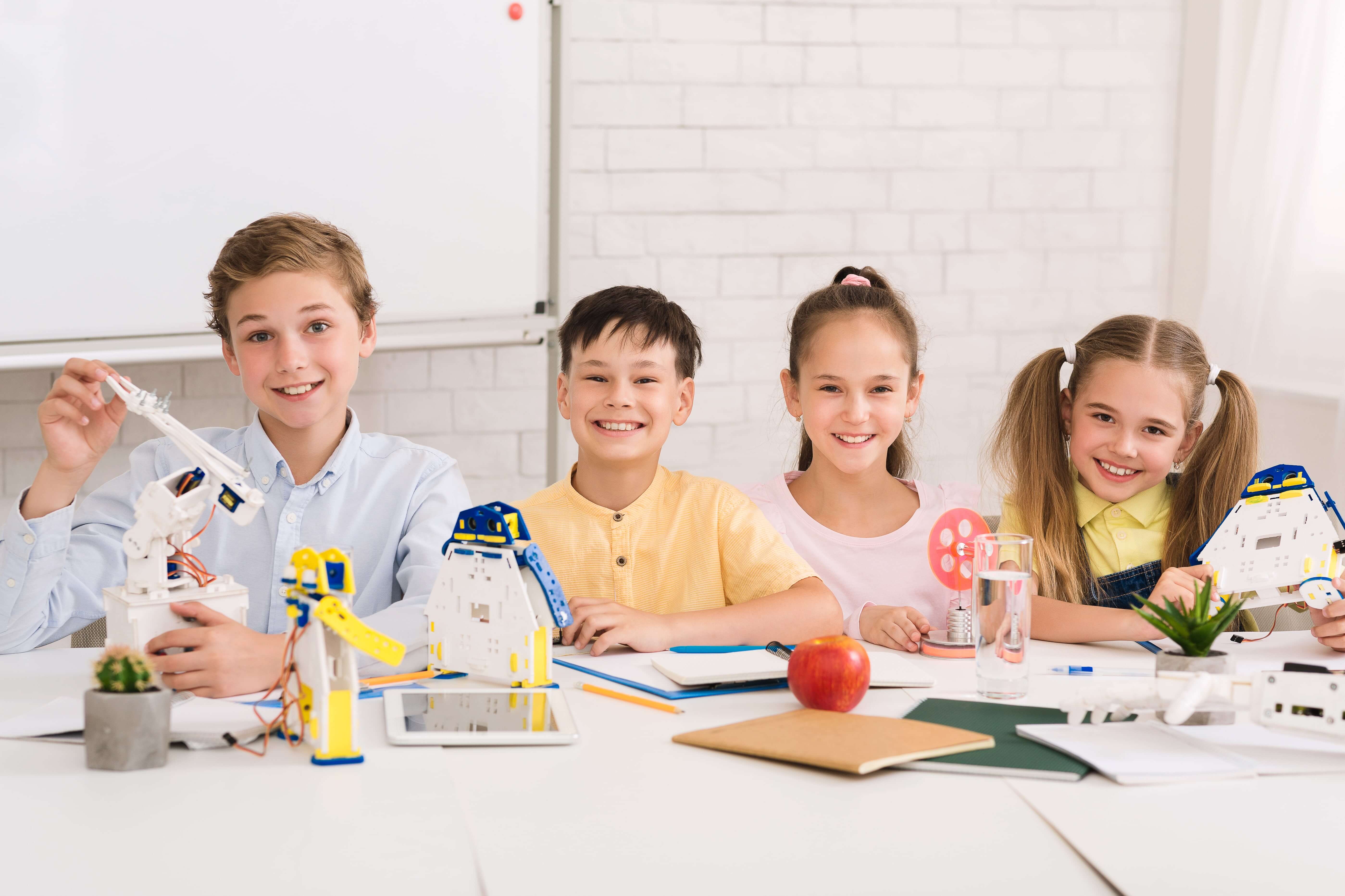 Four smiling kids in a robotics class